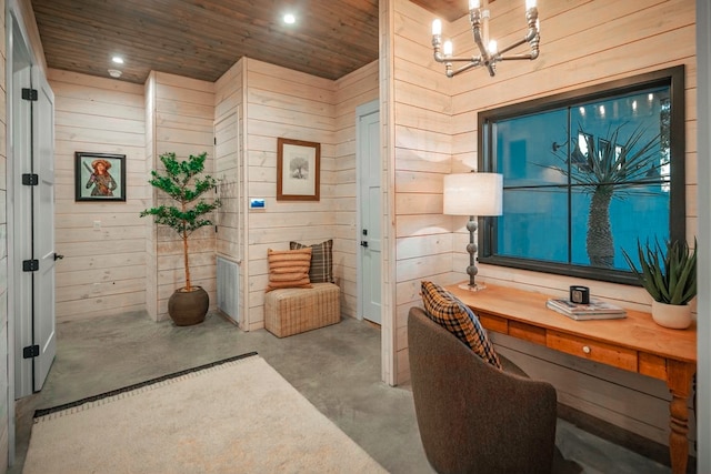 interior space with concrete flooring, wooden walls, wood ceiling, and an inviting chandelier