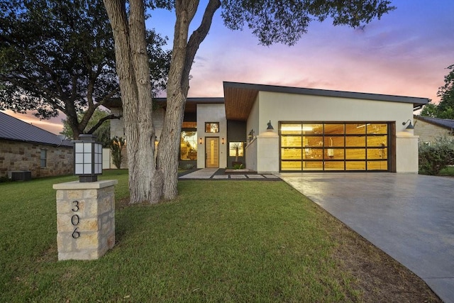 modern home with a garage, a yard, and central AC