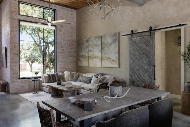 living room with a barn door, a wealth of natural light, a towering ceiling, and concrete floors