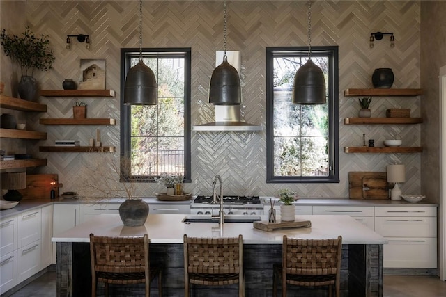 kitchen featuring a breakfast bar area, tasteful backsplash, white cabinets, and hanging light fixtures