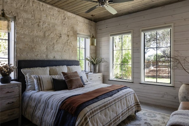 bedroom featuring ceiling fan, wood ceiling, wooden walls, and concrete flooring