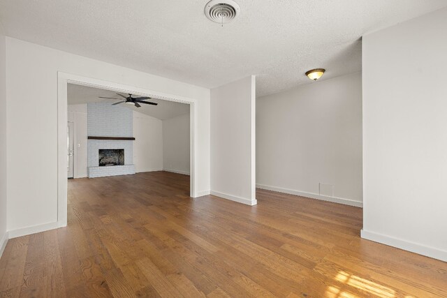 unfurnished living room with a fireplace, hardwood / wood-style floors, a textured ceiling, and ceiling fan