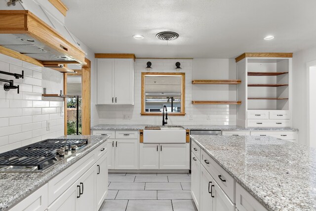 kitchen featuring white cabinets, sink, range hood, tasteful backsplash, and stainless steel gas cooktop