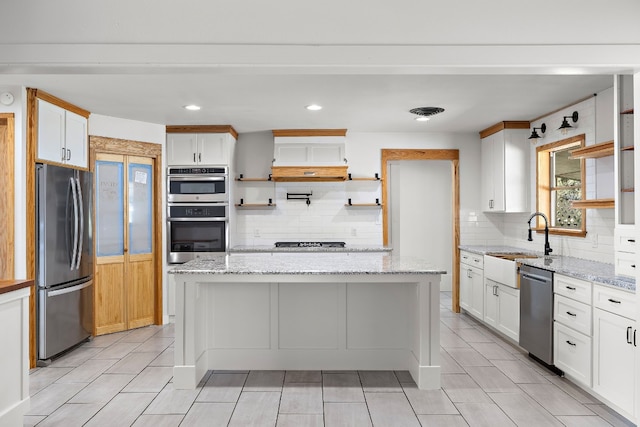 kitchen with light stone counters, white cabinets, stainless steel appliances, and a kitchen island