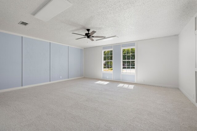 empty room with ceiling fan, light colored carpet, and a textured ceiling