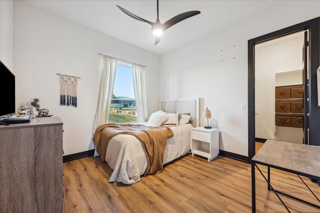 bedroom with light wood finished floors, baseboards, and a ceiling fan