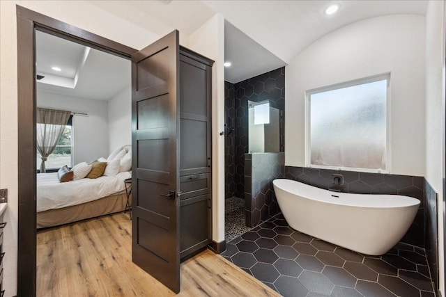 ensuite bathroom with walk in shower, a freestanding tub, tile walls, connected bathroom, and wood finished floors