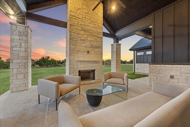 patio terrace at dusk with ceiling fan, a yard, and an outdoor living space with a fireplace