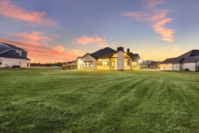 back house at dusk featuring a yard