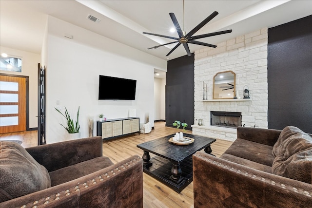 living room featuring ceiling fan, light hardwood / wood-style flooring, and a fireplace