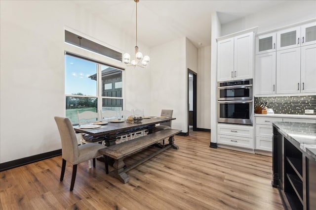 dining room with a chandelier, light wood-style floors, and baseboards