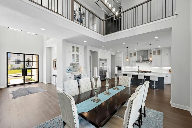 dining area with a towering ceiling and dark wood-type flooring