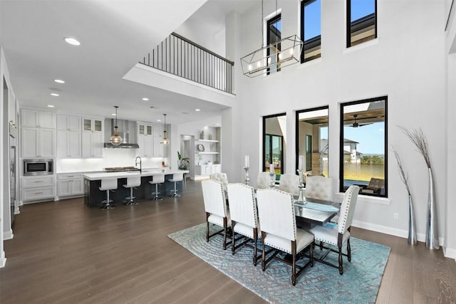 dining space with sink, a towering ceiling, and dark wood-type flooring