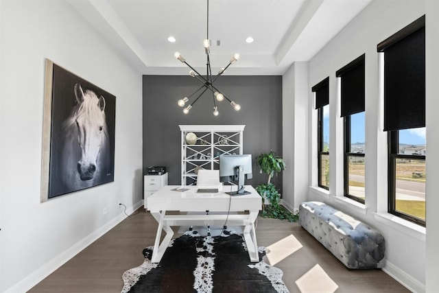 office area with dark hardwood / wood-style flooring, a tray ceiling, and a notable chandelier