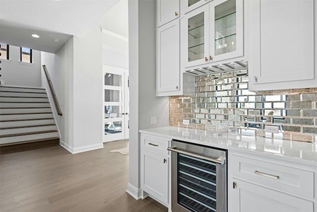 bar featuring backsplash, wine cooler, hardwood / wood-style floors, and white cabinets