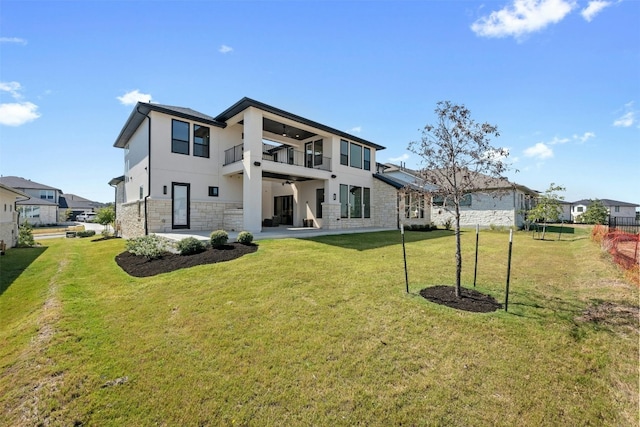 back of property with a yard and a balcony