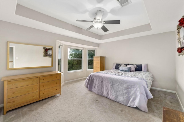 bedroom with ceiling fan, a tray ceiling, and carpet floors