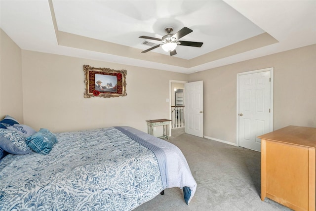 carpeted bedroom with ceiling fan and a tray ceiling