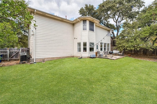 rear view of property with a patio, a yard, a fenced backyard, and central AC