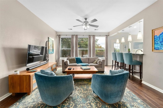 living room with wood finished floors, visible vents, and baseboards