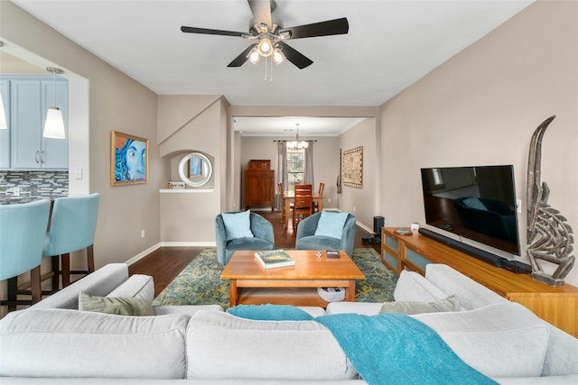 living room featuring ceiling fan with notable chandelier and dark hardwood / wood-style floors