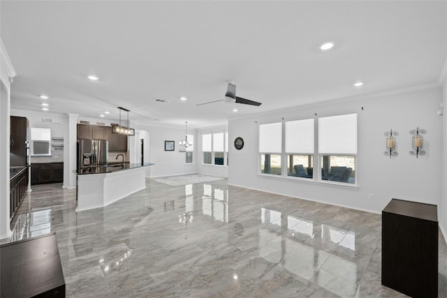 unfurnished living room featuring ornamental molding, sink, and ceiling fan with notable chandelier