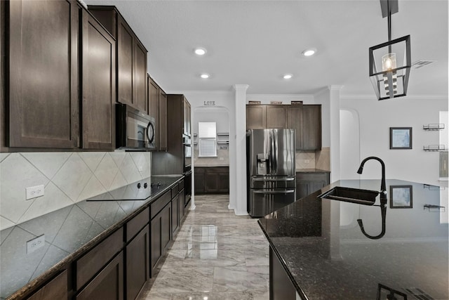 kitchen featuring appliances with stainless steel finishes, sink, hanging light fixtures, dark brown cabinetry, and dark stone counters