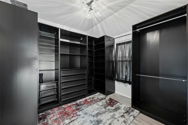 spacious closet featuring a notable chandelier and hardwood / wood-style floors