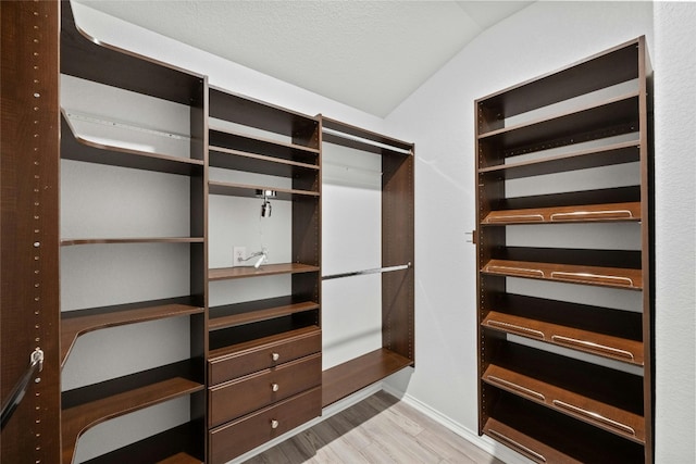 walk in closet featuring vaulted ceiling and light wood-type flooring