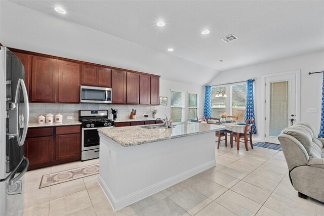 kitchen with appliances with stainless steel finishes, sink, an island with sink, hanging light fixtures, and vaulted ceiling