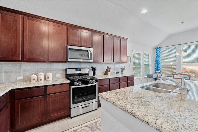 kitchen with tasteful backsplash, vaulted ceiling, stainless steel appliances, sink, and decorative light fixtures