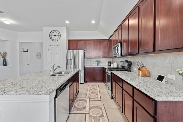 kitchen featuring decorative backsplash, an island with sink, appliances with stainless steel finishes, light tile patterned flooring, and sink