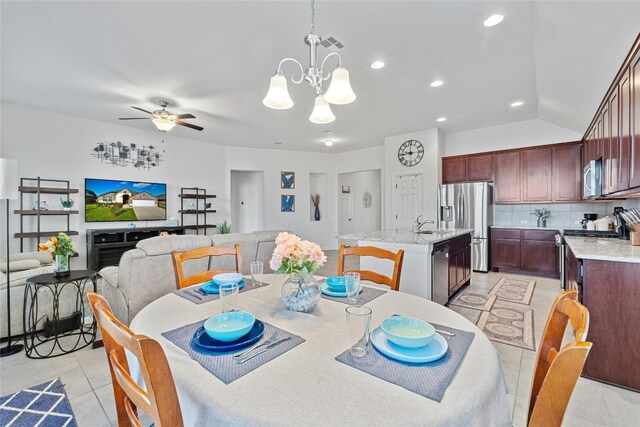 dining room featuring lofted ceiling, sink, ceiling fan with notable chandelier, and light tile patterned floors