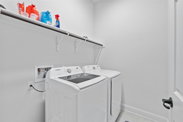 clothes washing area with washing machine and dryer and light tile patterned floors