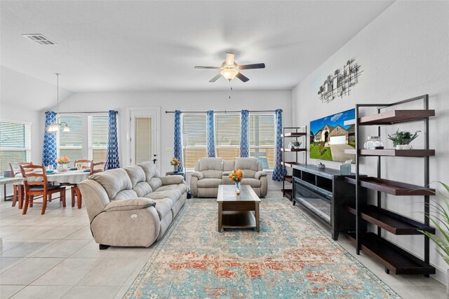 living room with lofted ceiling, light tile patterned flooring, and ceiling fan with notable chandelier