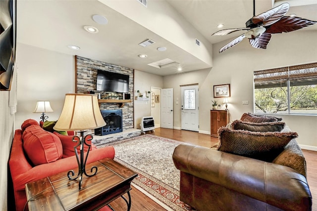 living room featuring light hardwood / wood-style flooring, heating unit, a fireplace, and a wealth of natural light