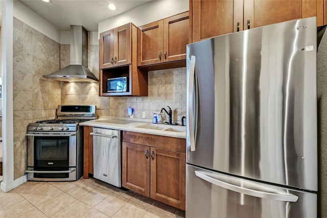 kitchen featuring decorative backsplash, wall chimney range hood, stainless steel appliances, sink, and light tile patterned floors