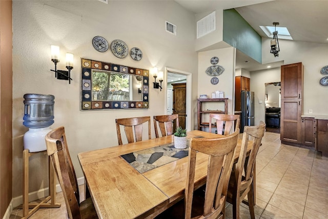 tiled dining room featuring high vaulted ceiling and a skylight