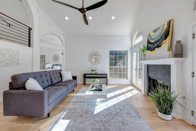 living room featuring ornamental molding, high vaulted ceiling, light wood-type flooring, and ceiling fan