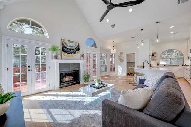 living room with french doors, high vaulted ceiling, and light wood-type flooring