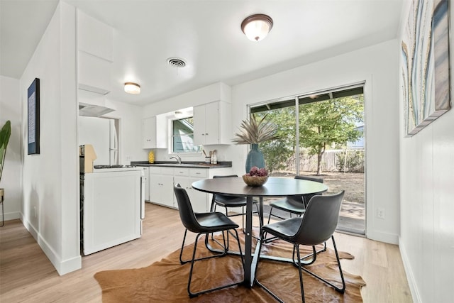 dining area featuring a wealth of natural light, sink, and light hardwood / wood-style flooring