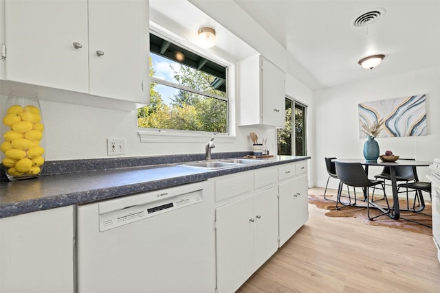 kitchen with white dishwasher, sink, light wood-type flooring, and white cabinets