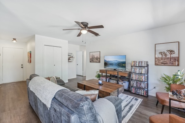 living room featuring dark wood-type flooring and ceiling fan