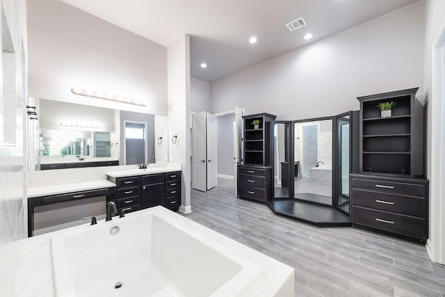 bathroom with hardwood / wood-style floors, vanity, a bathtub, and a high ceiling