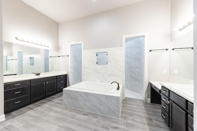 124 Park Place Dr, Georgetown, TX 78628 - bathroom featuring a bath, two vanities, tile walls, and wood finished floors