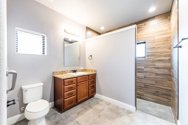 bathroom with toilet, a tile shower, and vanity