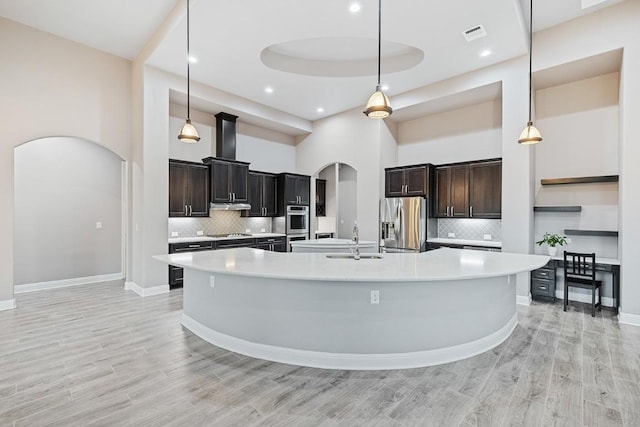 124 Park Place Dr, Georgetown, TX 78628 - kitchen featuring arched walkways, stainless steel fridge, a high ceiling, black stovetop, and light countertops