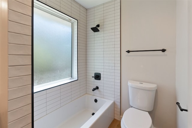 bathroom with toilet and tiled shower / bath combo