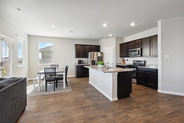 kitchen featuring sink, stainless steel appliances, dark hardwood / wood-style floors, and a center island with sink