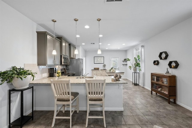 kitchen featuring kitchen peninsula, decorative light fixtures, a breakfast bar, and stainless steel appliances